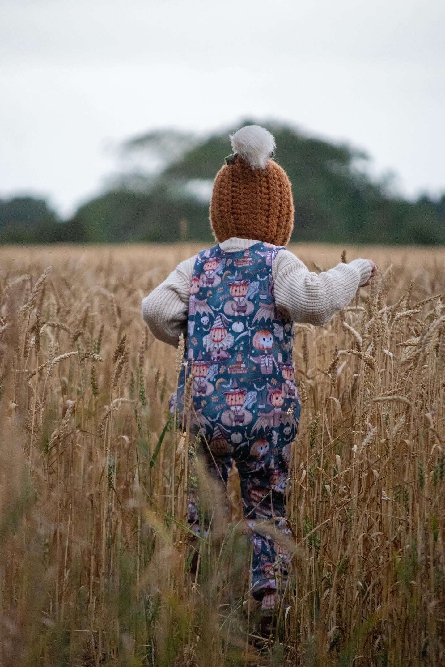 Handmade clothing Halloween romper fit for cloth. Boy in field running in crocheted hat and cream jumper. 